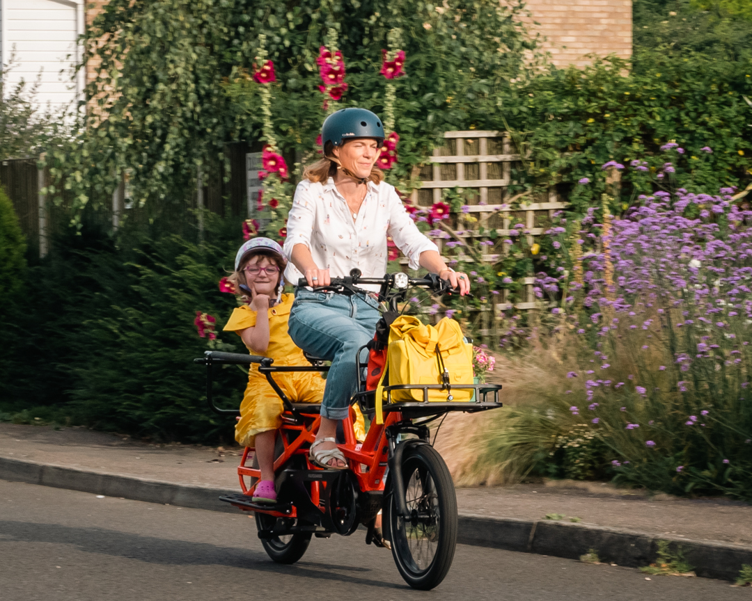 Caz Conneller rides an orange Tern GSD ecargo velocipede with 5 year old daughter on the back